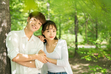 A lovely young couple are having fun in a forested park.