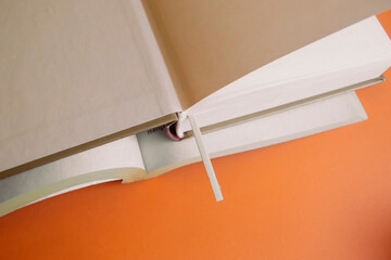 Open books with bookmark on an orange background. There is a wooden bookmark in the book.