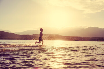little boy runs happily into the sea