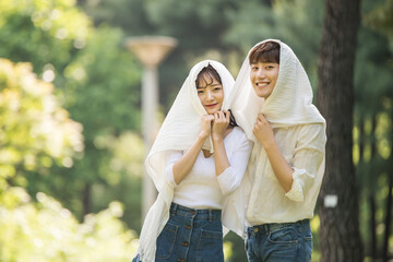 A young couple using a large towel to have fun in a forested park