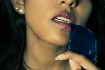 a beautiful brown south asian  woman with a condom pack on her mouth ,advertisement