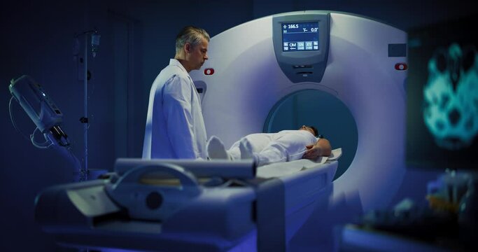 In Medical Laboratory Male Radiologist Controls MRI or CT or PET Scan with Female Patient Undergoing Procedure. High-Tech Modern Medical Equipment. Footage In Medical Laboratory or Healthcare Facility