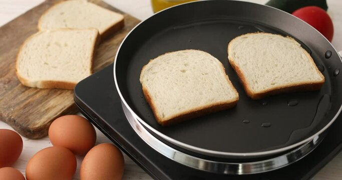 The bread is fried in butter or oil in a frying pan with steam. Making toast or croutons. Cooking food. Preparing breakfast. Close-up.