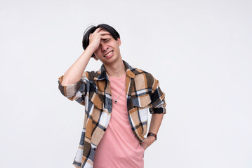 A young frustrated asian man face palms from stress. Screwing up and realizing his blunders....