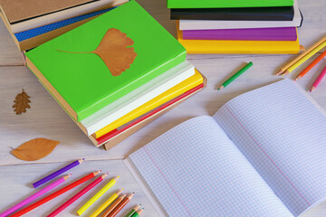 Autumn concepts. Stacks of different multicolored books, open notebook,  and colored pencils on...