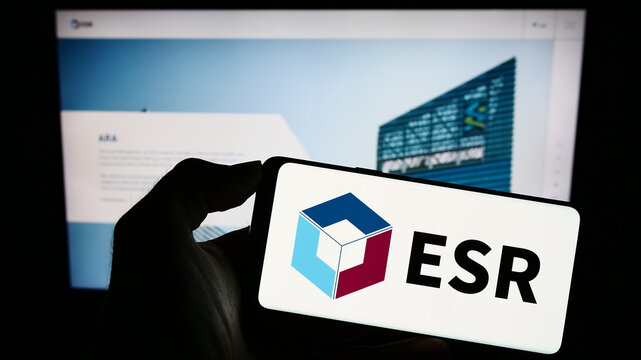 Stuttgart, Germany - 09-06-2023: Person holding mobile phone with logo of real estate company ESR Group Limited on screen in front of business web page. Focus on phone display.