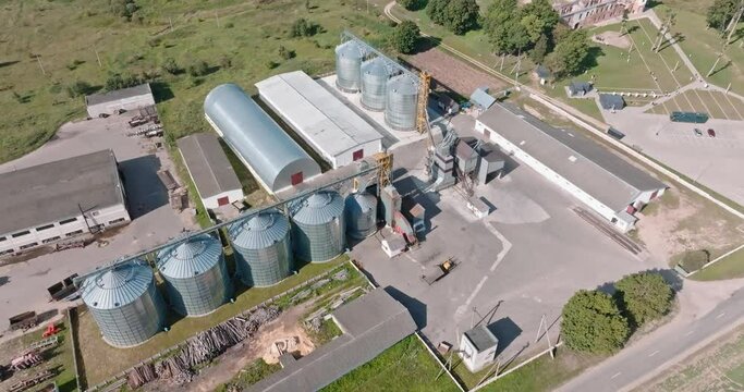 aerial view over modern granary elevator. Silver silos on agro-processing and manufacturing plant for processing drying cleaning and storage of agricultural products, flour, cereals and grain. 