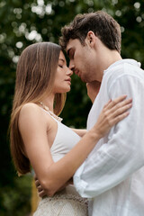 side view of handsome man kissing girlfriend in crop top and standing together outdoors, romance