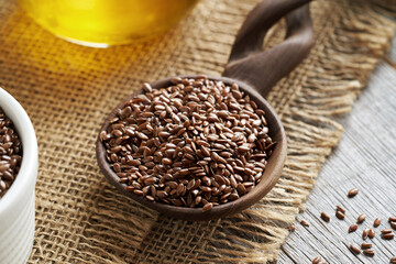 Flax seeds on a spoon, with flax seed oil in the background