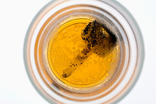Looking Down Into A Partially Full Beer Glass With A Car Key On The Bottom Of The Glass