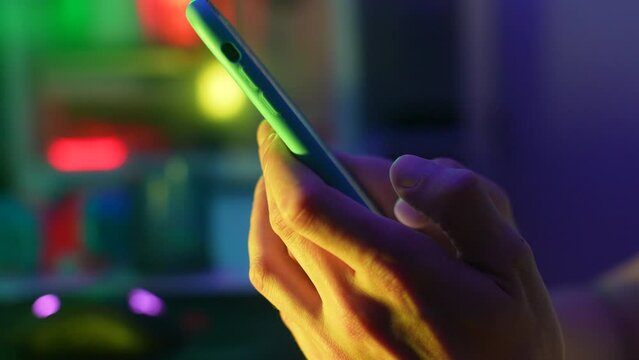 Closeup side view of unrecognizable young man touching scroll page app on mobile phone. Close-up male fingers browsing movie video in internet library to watch film online. Shooting in slow motion.