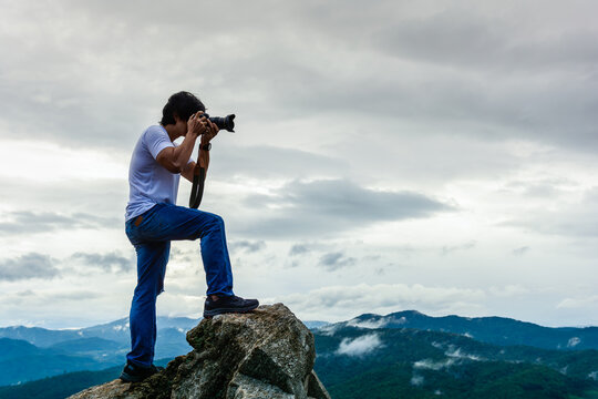 Photographer takes photos on the peak of rocks mountain after rain show fresh air and clear view of mountain, success,winner, leadership concept.
