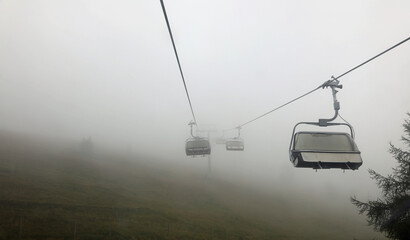chairlift without people immersed in fog in the mountains