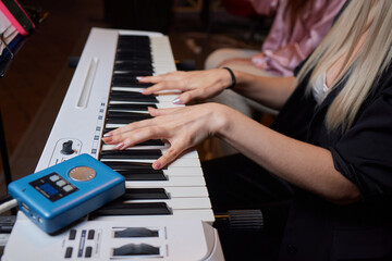 Fototapeta na wymiar Closeup of female hands on an electronic piano. A laptop on a keyboard instrument.