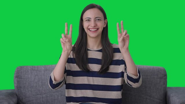 Happy Indian girl showing victory sign Green screen