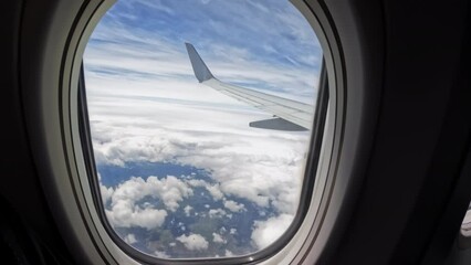Aircraft plane Wing of flying in clouds and blue sky airplane as seen by passenger through porthole windows. Move camera