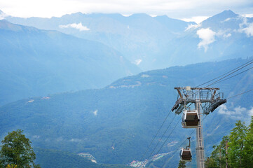 A cable car with a cabin going down from the mountain.