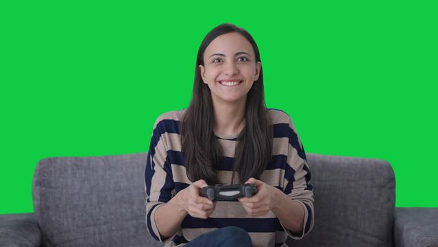 Happy Indian girl gamer playing video games Green screen