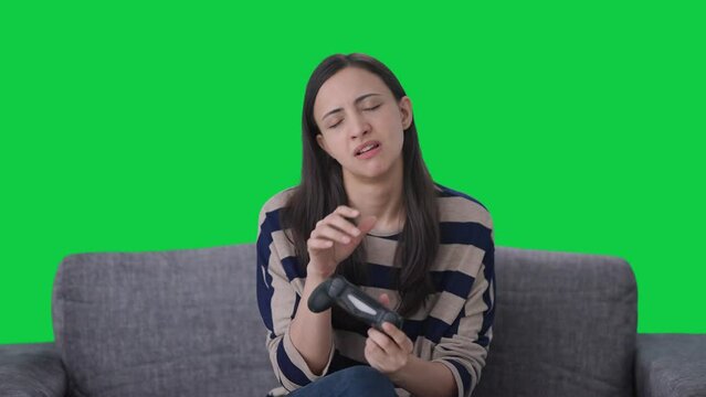 Tired Indian girl gamer playing video games Green screen