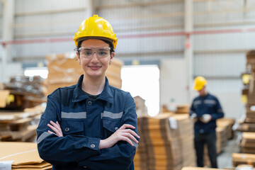 Portrait of woman warehouse worker wearing uniform and helmet safety standing arms crossed working...