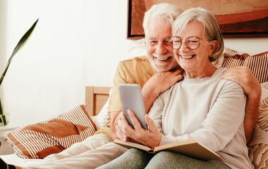 Video call concept. Portrait of happy handsome senior couple together in bed using phone webcam for...