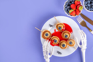 Funny kids breakfast for Halloween. Creative homemade sweet pancakes in form of traditional Halloween monsters and symbols, with fresh berry, chocolate and red syrup