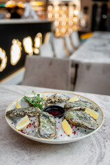  Plate with oysters on ice and sauce on a marble table