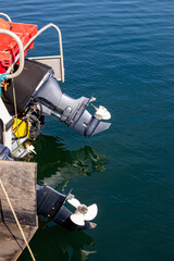 Outboard motor and 2 raised clean white 3 bladed propellers, with reflections in the water, glinting in the sun