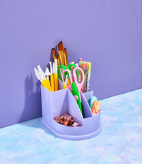 Collection of school supplies. A stationery stand with scissors, paint brushes and other office supplies.