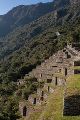 Terraces at the archaeological site of Machupicchu, surrounded by mountains and blue sky and vegetation, Sacred Valley, Peru. 