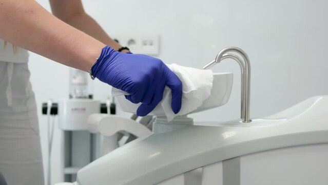 cleaning dental office wipe moisture with sterile cloth equipment sink for spitting dental chair disinfection neatness cleanliness neatness girl nurse with wet napkin in hygiene gloves. cleaning