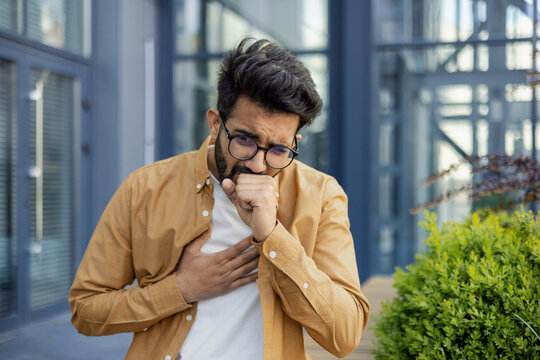 A sick man sits on the street, a businessman coughs outside an office building, a Latin American woman in casual clothes has a cold on a sunny day.