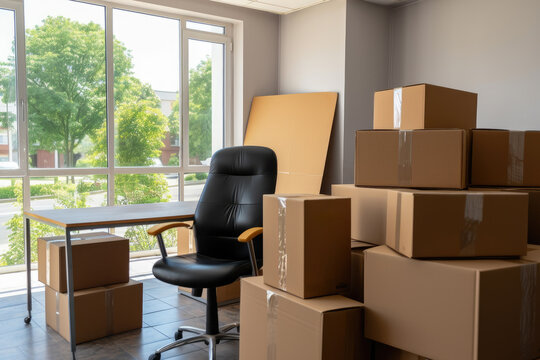 Moving to new office, home office, relocating, crisis, remote working, start new business, e-commerce concept. Stack of cardboard boxes with stuff, table desk and office chair in empty office room