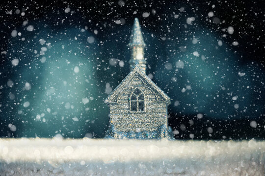 New Year Christmas background. Silver figurine of a church building and falling snow. Night fabulous atmosphere of winter holiday evenings.