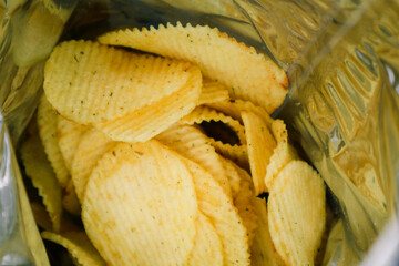 Crispy potato chips in aluminum metal bag package. The concept of an unhealthy food and lifestyle.