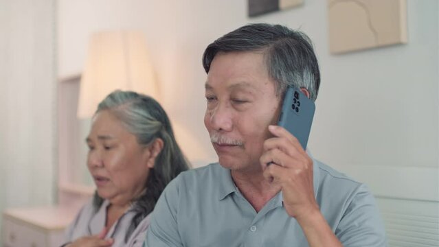 Medium shot of mature man calling to doctor while sitting next to his sick suffocating wife at bedroom