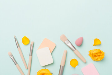 Makeup brushes and sponges on color background, top view