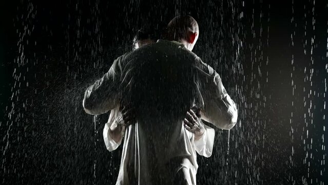 brawny man and fragile woman embracing in rain in night, male back silhouette in darkness
