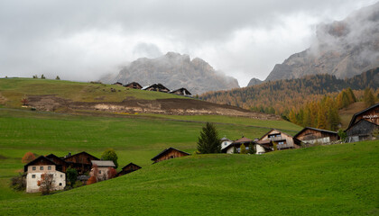 Fototapeta na wymiar Traditional wooden cottage mountain houses in the green field in the dolomites. Housing in Italian apls. Alpine region