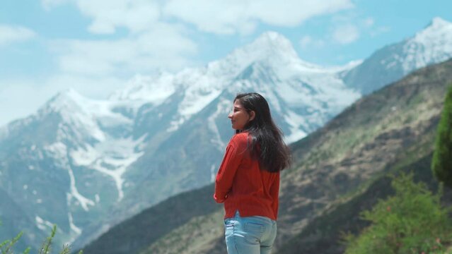 Indian woman in the mountains. Girl on mountain looking at beautiful snowy peaks in winter at Lahaul, Himachal Pradesh, India. Travel and holidays concept. Girl in the winter wonderland of India.