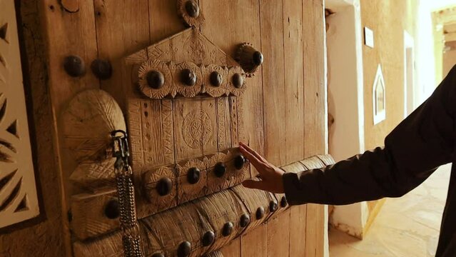 Old wooden door in Jeddah Saudi Arabia. Man's hand touching the door surface