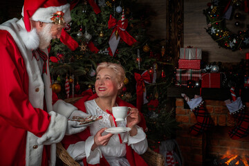 Santa Claus and wife Mrs. Claus near fireplace