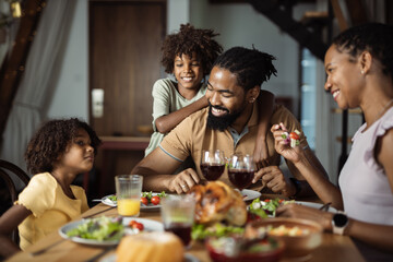 Happy African American family enjoying in meal at dining table - obrazy, fototapety, plakaty