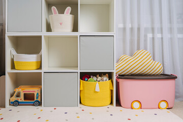 White shelving with colorful storage baskets and boxes with toys. Interior design. Organizing and storage ideas in children room. Interior design. Playroom