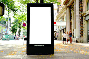 billboard on busy street. blank white poster and advertiser ad space. digital outdoor display lightbox. base for mockup. empty display panel. soft streetscape. urban shopping alley background - obrazy, fototapety, plakaty