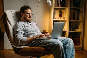 A man is working late from home on laptop.