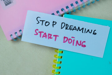Concept of Stop Dreaming Start Doing write on sticky notes isolated on Wooden Table.