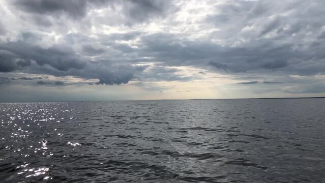 dramatic seascape, dark clouds over the sea, horizon, shot from a boat in motion