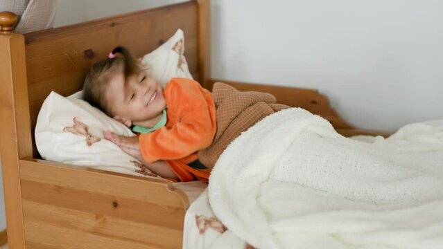 A little cute girl sleeps in a crib in a bright room at home.