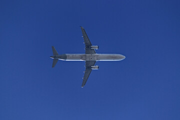 low view of a jet plane flying at low altitude under a cloudless blue sky.